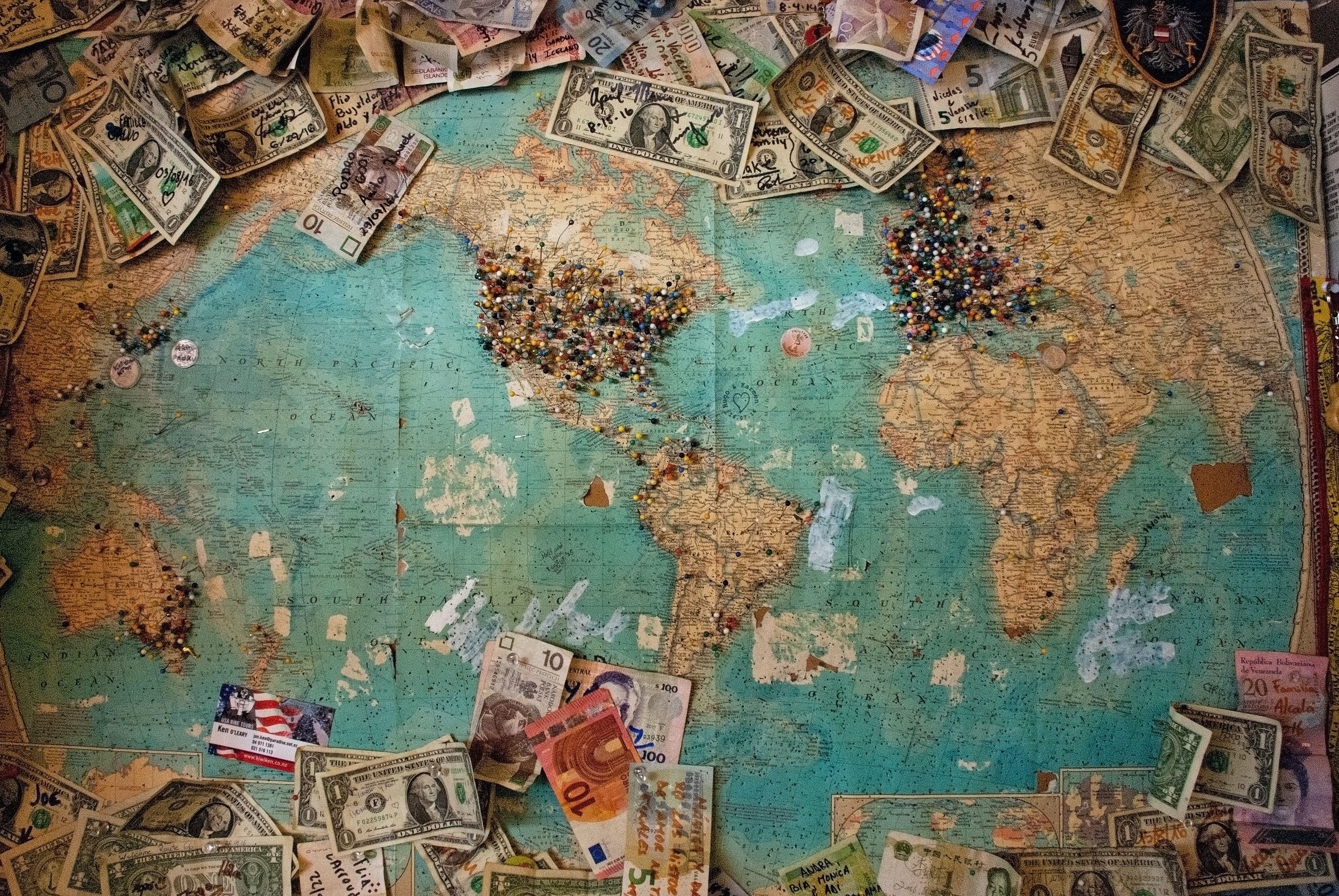 Photo of a world map covered in push pins and cash