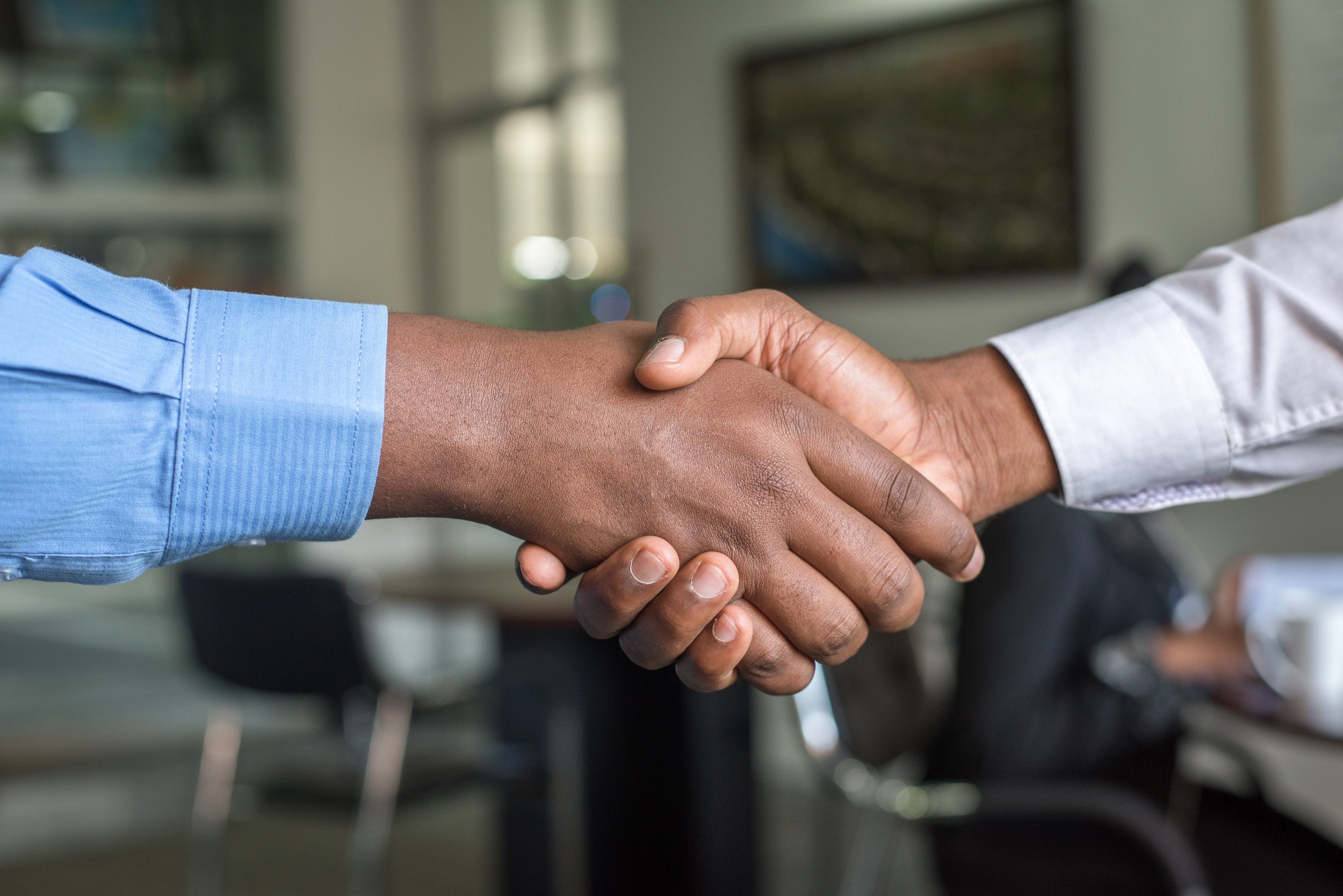 Photo of two Black people in business outfits shaking hands.