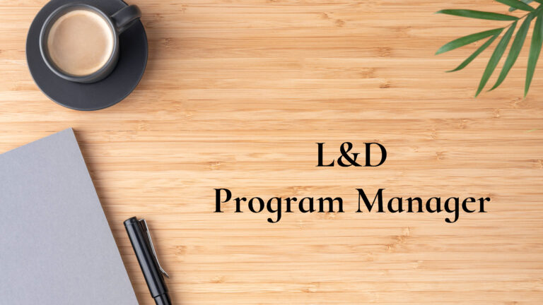 Overhead view of a wooden desk with coffee and a notebook and the text L&D Program Manager
