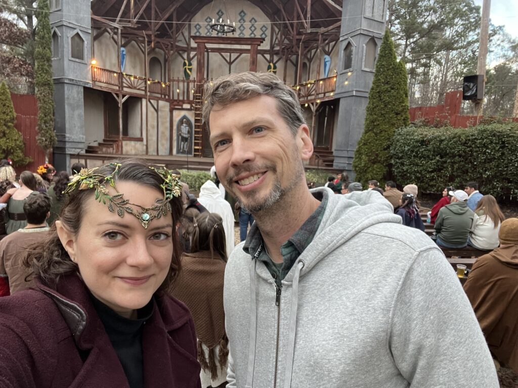 The author is pictured at a Renaissance Festival wearing elf ears and a fairy crown.