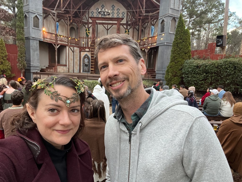 The author is pictured at a Renaissance Festival wearing elf ears and a fairy crown.